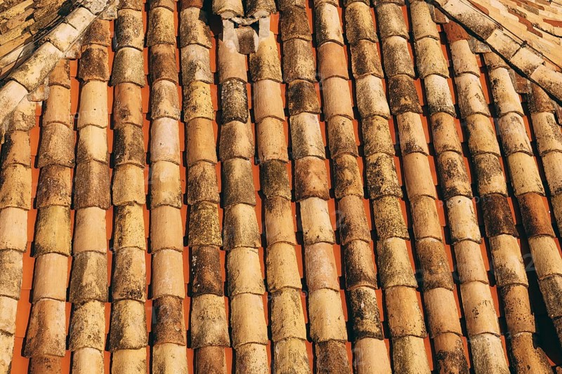 The texture of the old brown shingles on the roof of the building.
