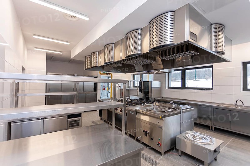 A contemporary commercial kitchen featuring stainless steel appliances and bright, efficient lighting