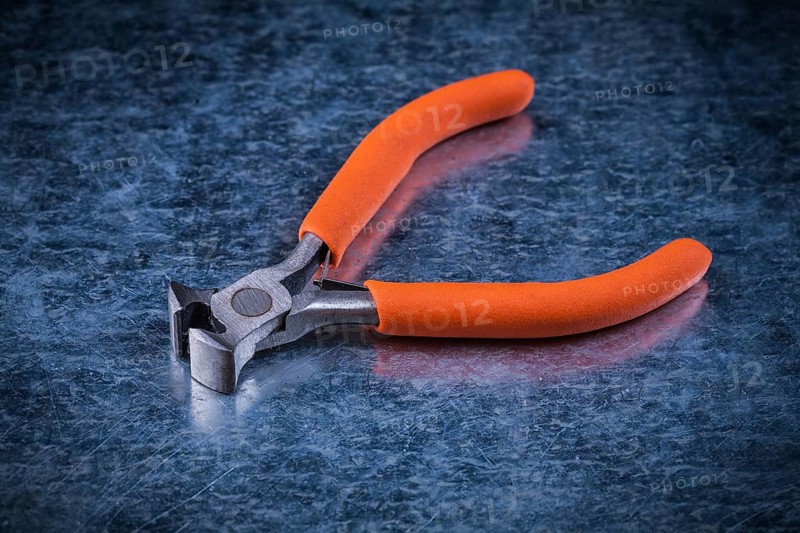 Insulated electric metal nippers on metallic background electricity concept