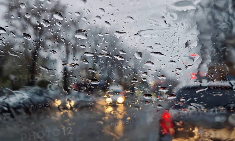 Melted snow and rain drops on the windshield of a car. Blurred outdoor view, winter season sleet as seen out of vehicle window