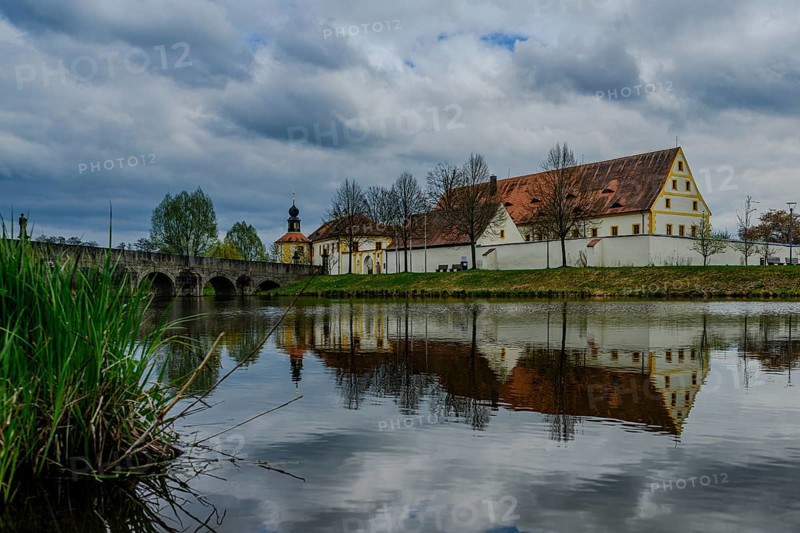 Old building and bridge reflected in a river under a cloudy sky, Tirschenreuth, Upper Palatinate, Bavaria, Germany, Europe