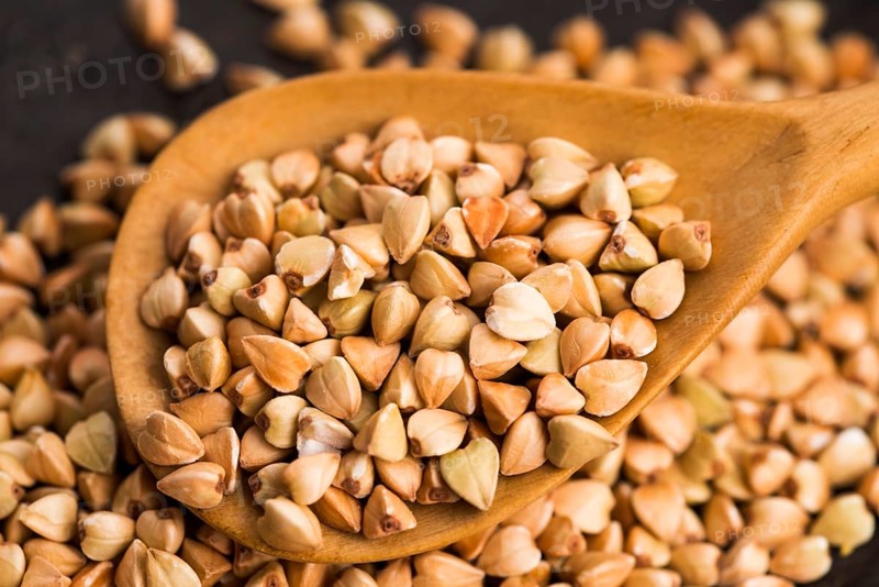 Buckwheat with a spoon on a wooden boards background