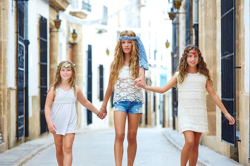 Kid girls walking hand in hand at white Mediterranean village of Spain