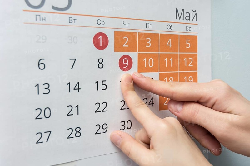 Child and adult hands indicate the date of May 9 wall calendar