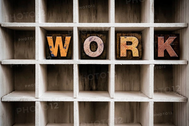 The word WORK written in vintage ink stained wooden letterpress type in a partitioned printer's drawer