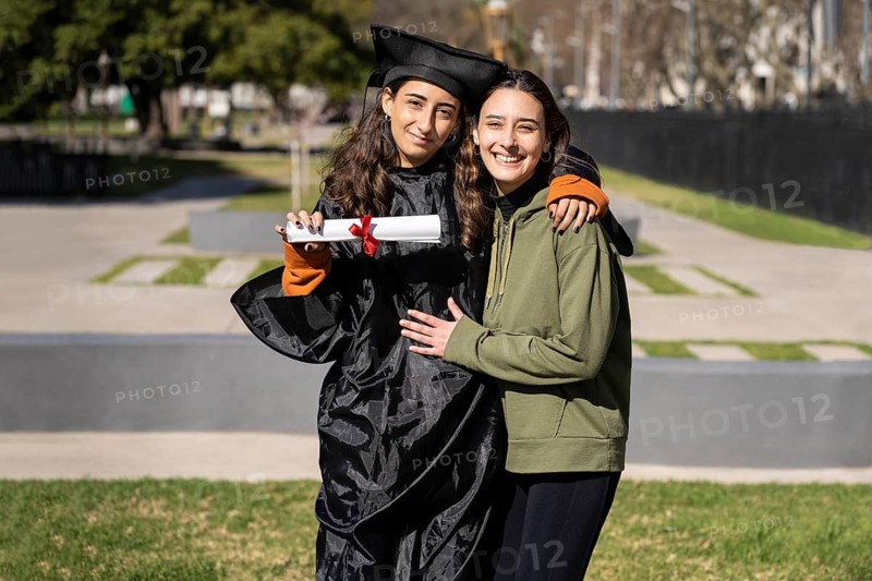 Recent graduate woman, dressed in cap and gown, showing off her degree celebrating with her family