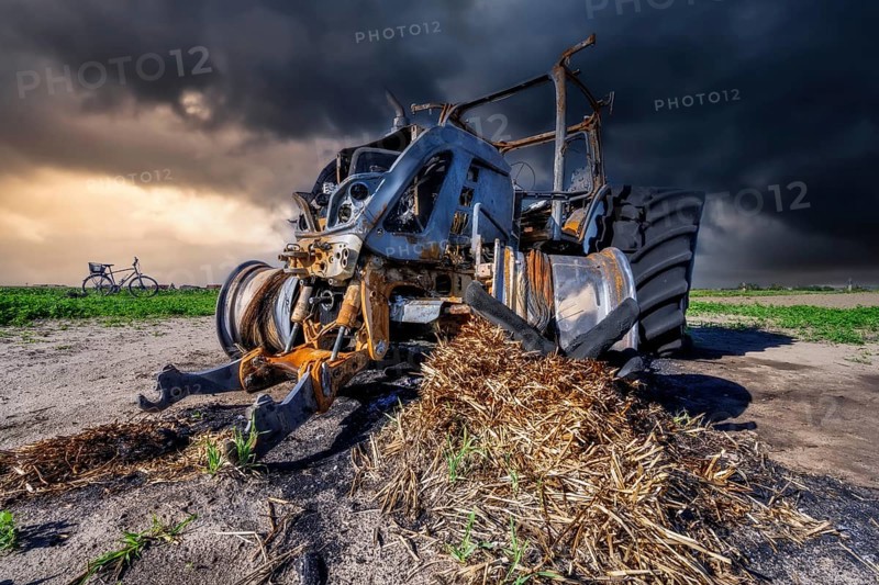 Fully destroyed burnt down tractor on a field