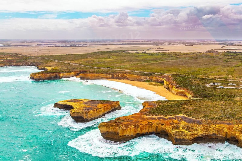 Helicopter flight over the scenic Pacific coastline. The fabulous journey to Australia. Cloudy cool summer day. Legendary cliffs Twelve Apostles in the snow-white foam of the ocean surf