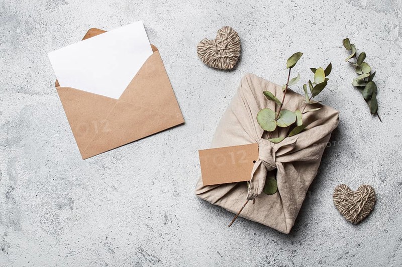 Zero waste Valentine's Day concept and mock up. Eco-friendly gift cloth wrapping in Furoshiki style, craft paper envelope, empty gift or greetings card. Top down view or flat lay. Copy space for design