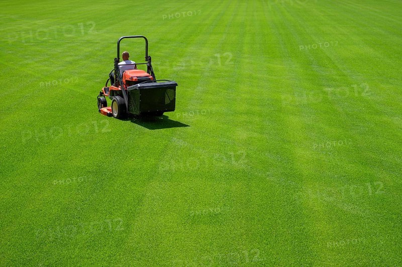 Mowing grass at the football stadium in Lubin, Poland, Europe