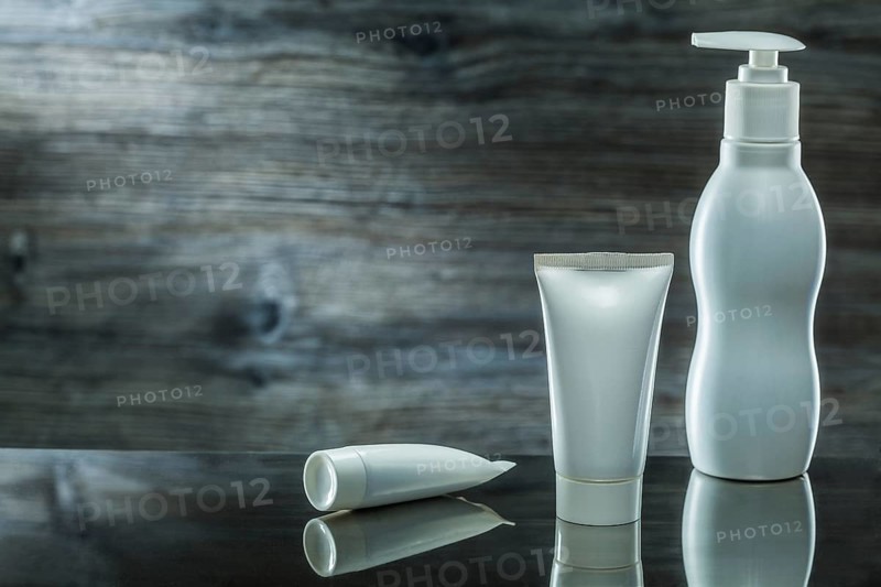 Tubes and sprayer skincare items on dark background