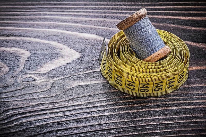 Vintage spool of thread tape measure on wooden board handicraft concept
