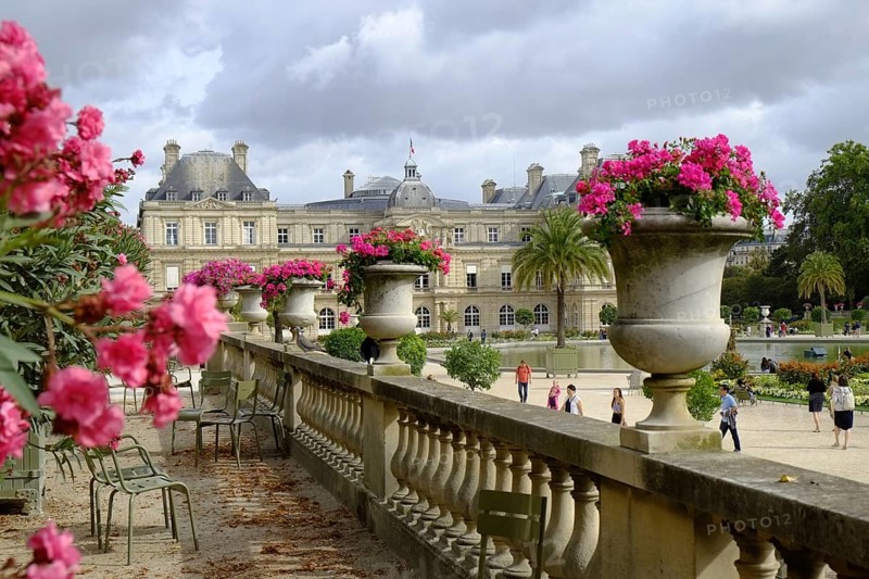 In the Jardin du Luxembourg: Raised terrace with stone balustrade and planted amphorae, well-tended parkland, the Palais du Luxembourg in the background. Landscape format. In Jardin du Luxembourg: elevated terrace with stone balustrade and planted amphorae, well-tended parkland, the Palais du Luxembourg in the background. Horizontal format