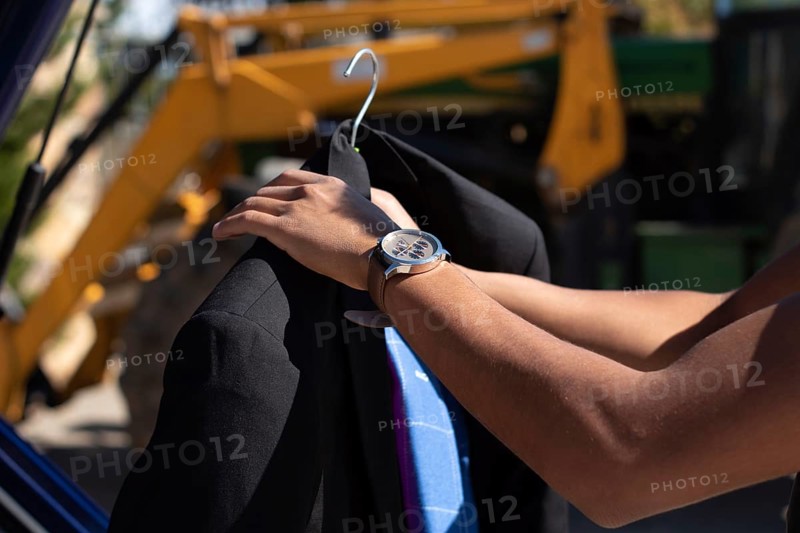Closeup of an unrecognizable latino man putting an american jacket on a hanger outside