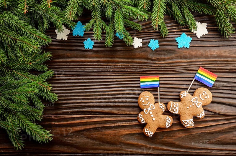 Christmas background of gingerbread man with flag spruce branches and colorful sugar snowflakes on wooden table