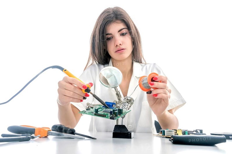 Woman Electronic Technician Repair Electronic Equipment using Electric Soldering Iron