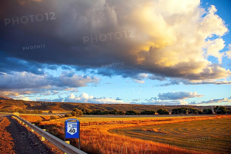 The endless Argentinean prairie and the famous Ruta 40 dirt road. A gigantic scenic thundercloud pierced by lightning strikes and illuminated by the sunset