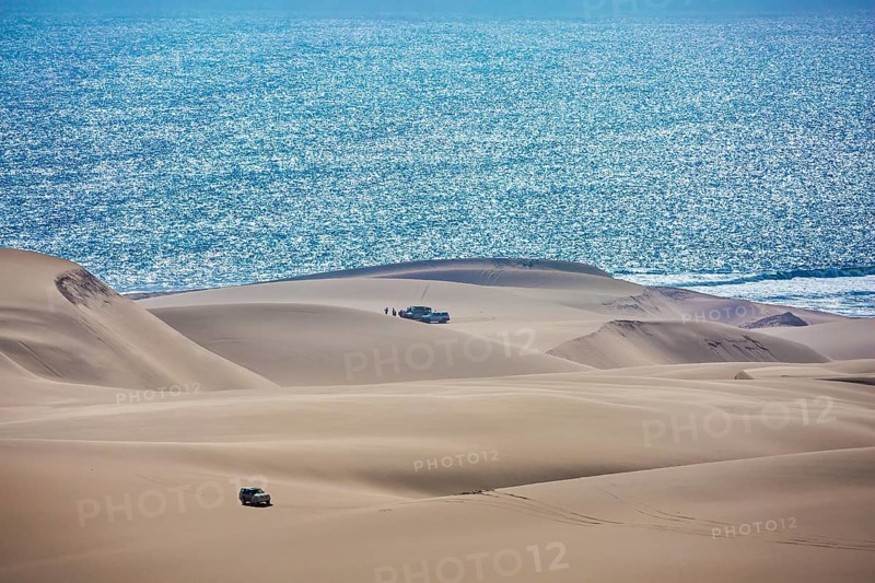 Gorgeous and dangerous jeep - safari through the huge sand dunes on the ocean shore. Atlantic coast of Namibia, south of Africa. The concept of exotic and extreme tours