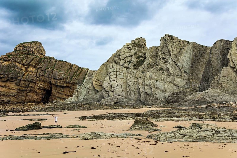 Noon on the beach of Playa di Arnia, Spain. Man admiring the magnificent scenery. Cantabria. Windy stormy day on the Atlantic coast