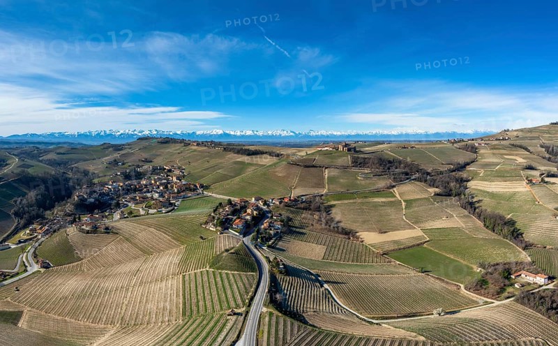 The hilly countryside in the Italian Piedmont with the village of Barolo and snow-covered mountains behind