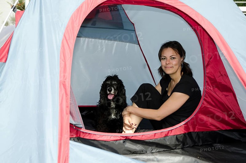 Woman Sitting Inside a Camping Tent with Her Cocker Spaniel Dog in a Sunny Summer Day in Switzerland