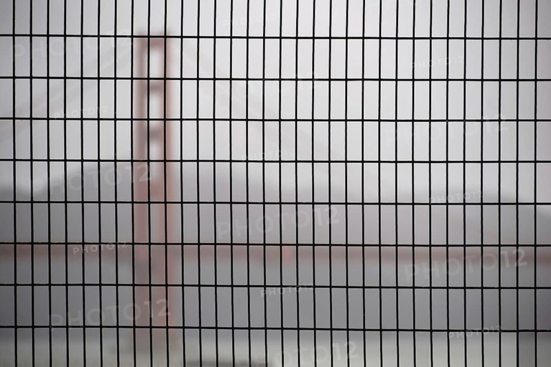 The Golden Gate Bridge blurred behind a fence in hazy rainy weather