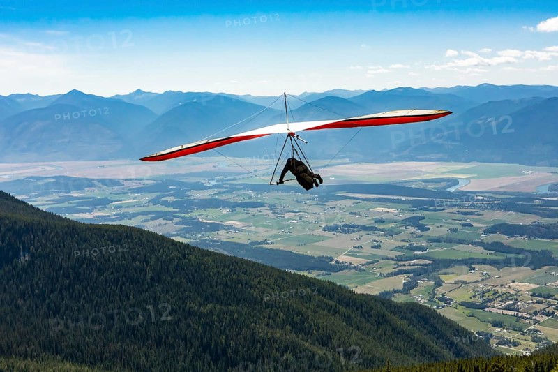 Long shot of flying extremal hang glider. Young man enjoying his recreational journey to Creston, British Columbia, Canada, North America