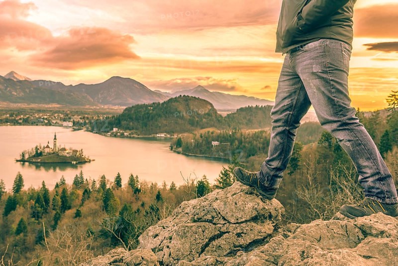 Man equipped with hiking shoes climbed on rocks above the lake Bled from Slovenia, in a December morning day