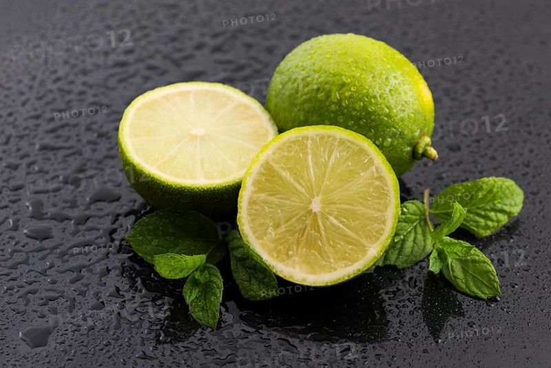 Green limes with mint and water drops on black background