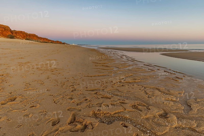 What a sandy beach on the Atlantic. Landscape shot at sunset on a coast with sandstone cliffs. Low tide on the yellow beach of Praia da Falésia near Albufeira, Algarve, Portugal, Europe
