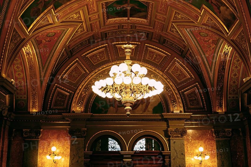 Large golden chandelier under the gilded ceiling in the interior.