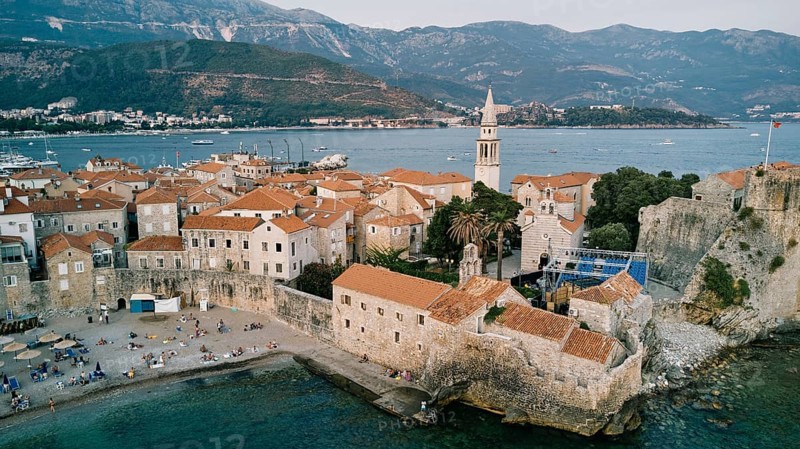 Stone fortress walls of the old town near the high bell tower. Budva, Montenegro. Drone.