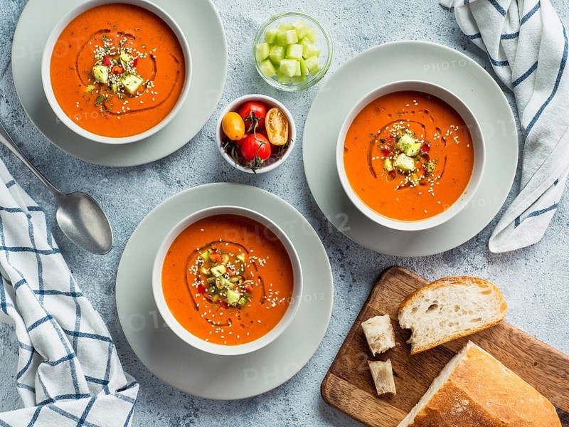Gaspacho soup on white marble tabletop. Three bowls of traditional spanish cold soup puree gaspacho or gazpacho on light gray or white marble background. Top view or flat lay