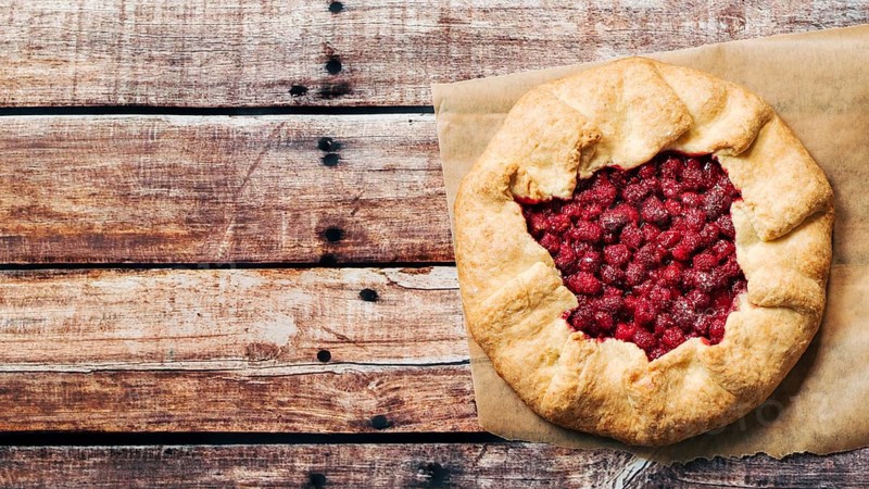 Perfect raspberry galette. Delicious rustic homemade tart with frozen or fresh raspberries on old wooden background. Beautiful round shape galette with raspberries, copy space. Top view or flat lay