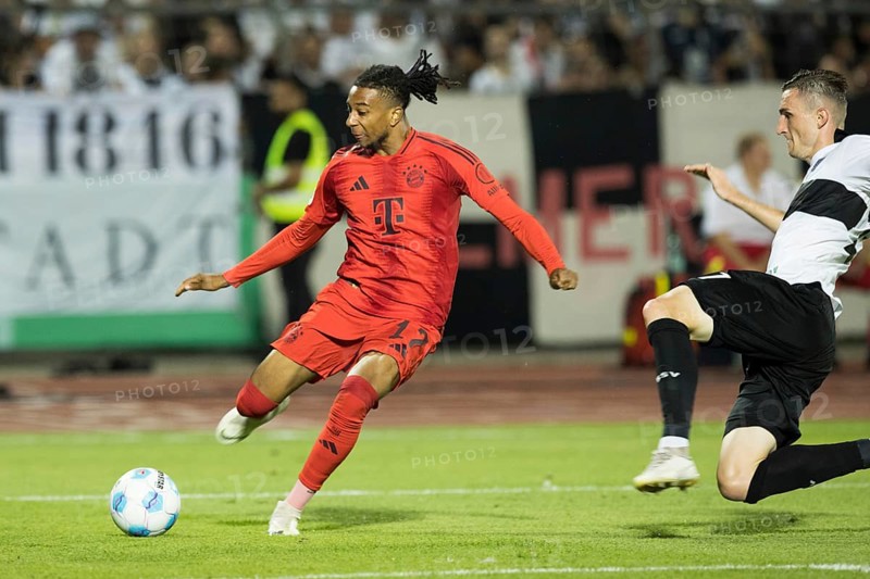 Football match, Michael Akpovie OLISE FC Bayern Munich left, crossing the ball, Niklas KOLBE SSV Ulm tries to stop him with a dive, Donaustadion football stadium, Ulm, Germany, Europe