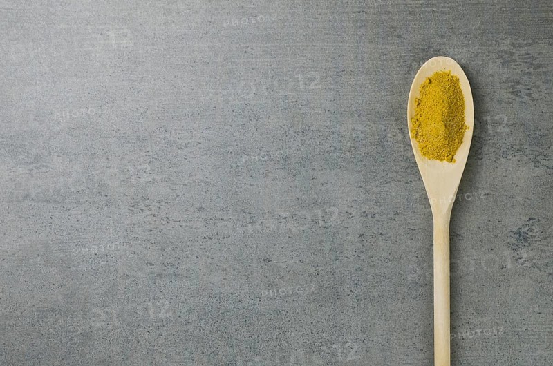 Turmeric spice in wooden spoon
