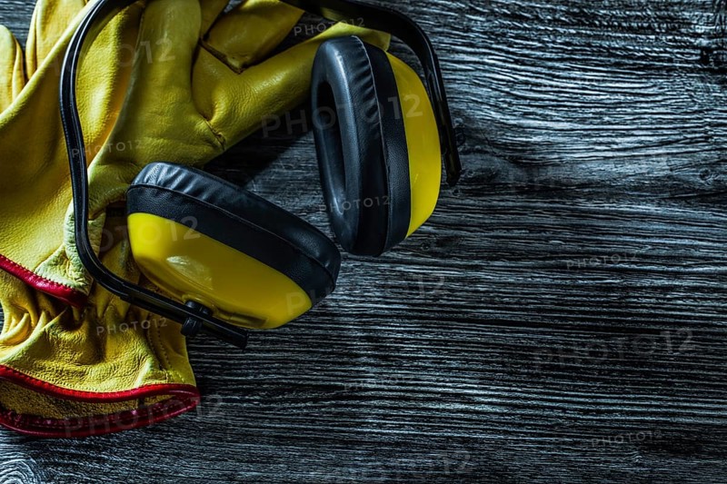 Protective earmuffs leather gloves on wooden board