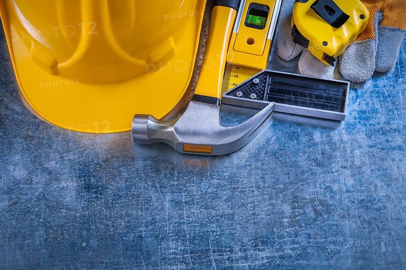 Safety gloves try square construction level tape-line hard hat and claw hammer on metallic background maintenance concept