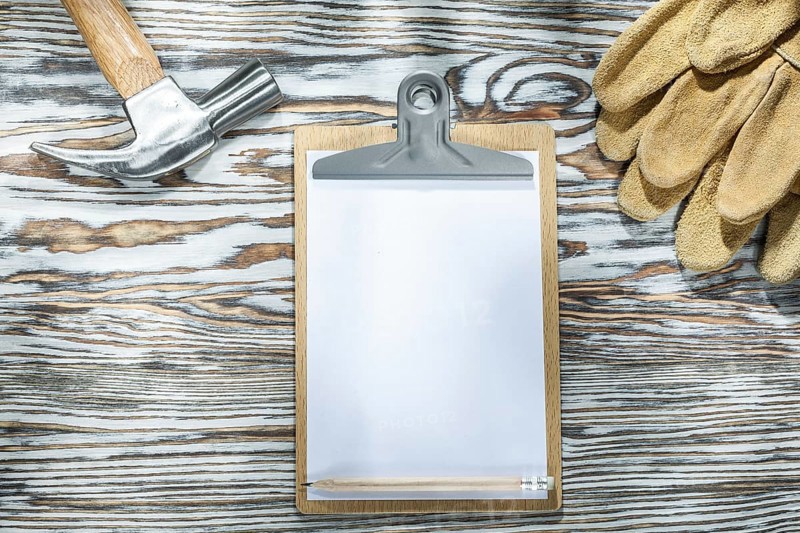 Protective gloves clipboard claw hammer on wooden board