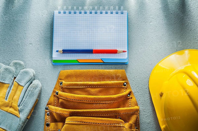 Protective gloves building helmet notebook pencil tool belt on concrete background