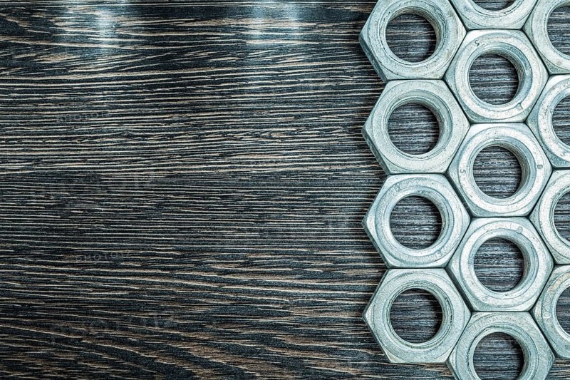 Stainless construction nuts on wooden board
