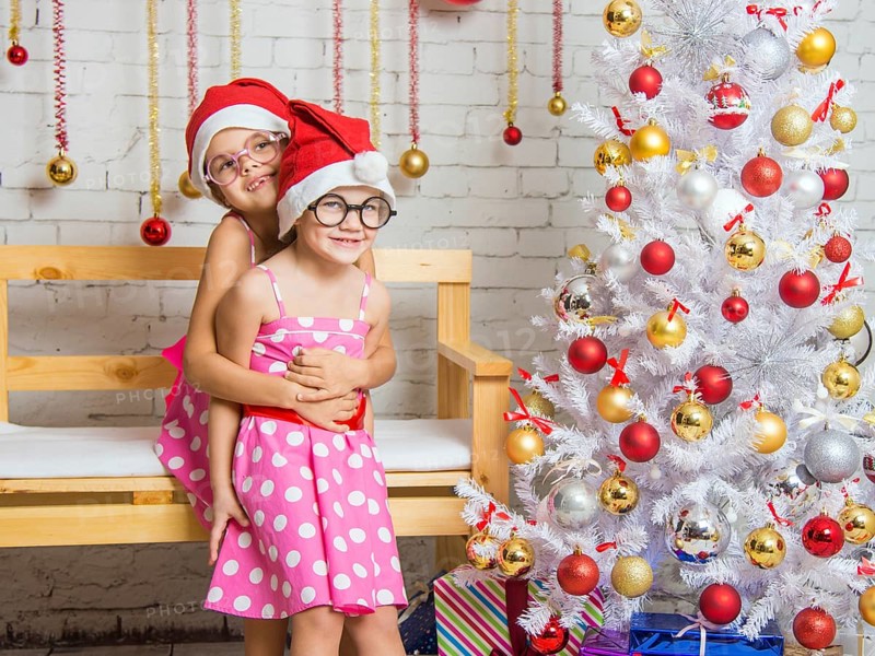 Two funny sisters four girls and six years of playing and having fun in the home New Years interior