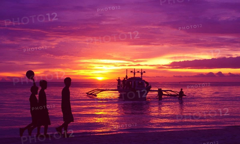 Philippines: Three local football boys walking on the beach on the island of Boracay