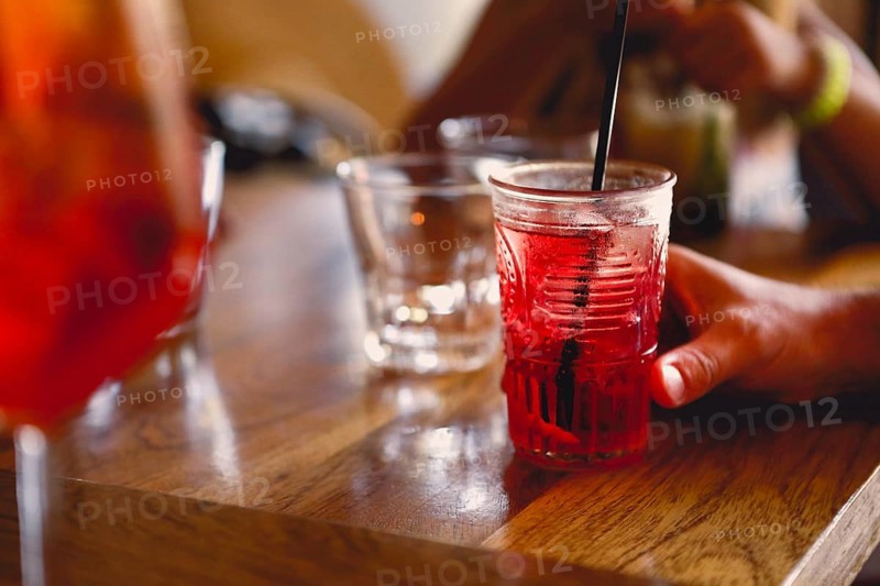 Unrecognizable person sitting at table and enjoying cool fruit cocktail on summer day in cafeteria