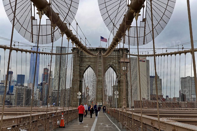 Brooklyn Bridge in Brooklyn, Manhattan, New York, USA United States of America, Brooklyn Bridge with passers-by and the American flag in an urban environment, New York City, USA, North America