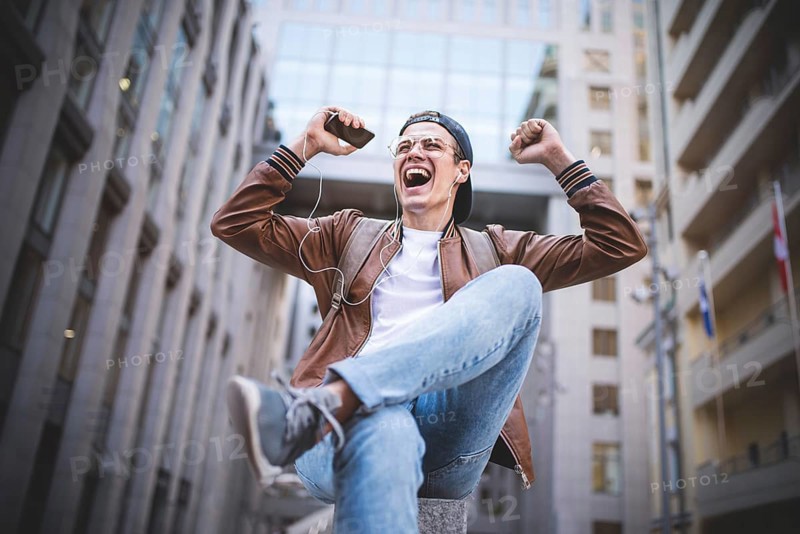 Man Sitting Listening Music Earphones Concept. Cheerful young guy listening the music