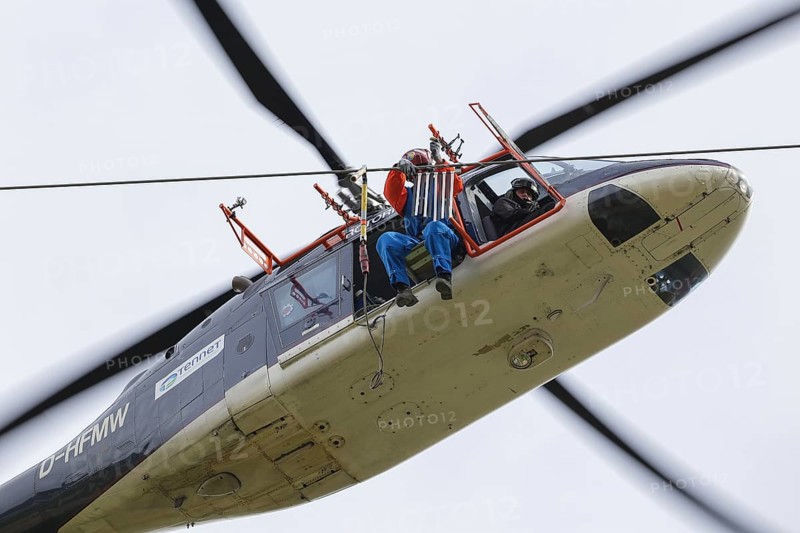 Installation of bird protection markings on overhead power lines by helicopter, worker installing bird deflectors on high-voltage power lines, close-up, 10 April 2017, Affoldern, Hesse, Germany, Europe