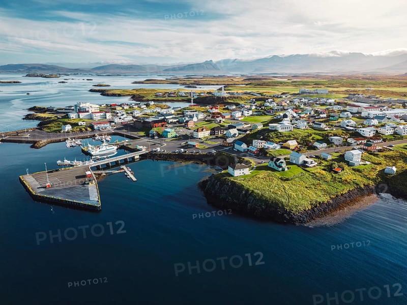 Beautiful aerial view of the Stykkisholmskirkja Harbor with Fishing ships boats at Stykkisholmur town in western Iceland. City view from Sugandisey Cliff with lighthouse. Famous colorful houses. September, autumn 2022