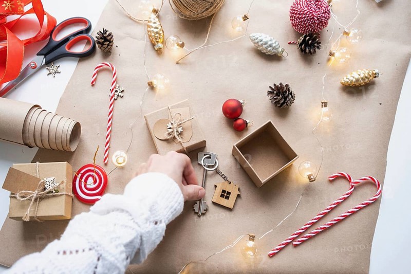 Key to house with keychain on cozy home in gift box with Christmas decor packaging. Pack present for New Year, Christmas. Building, project, moving to new house, mortgage, rent, purchase real estate
