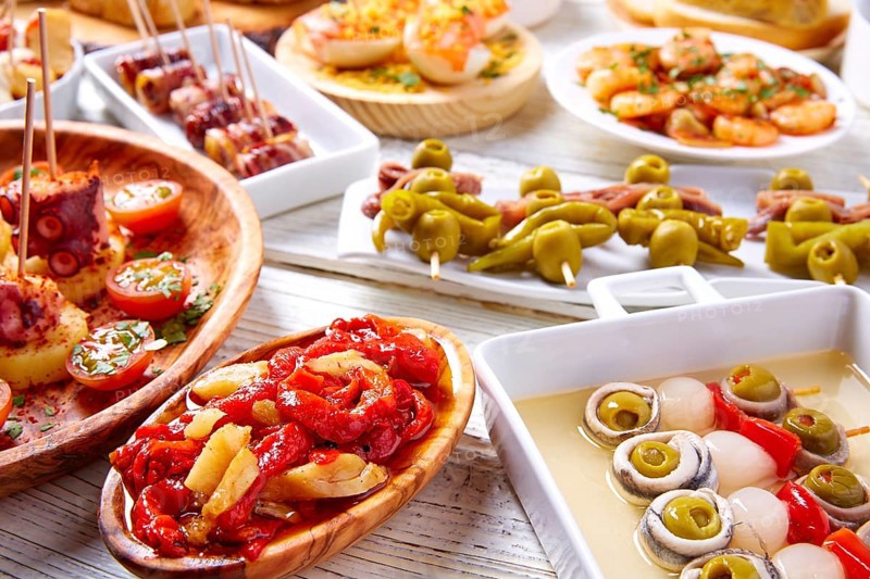 Tapas mix and pinchos food from Spain recipes also pintxos on a white wood board